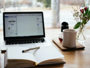 Ein Laptop und ein Notebook auf einem Holztisch.